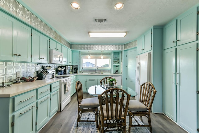 kitchen featuring visible vents, a sink, white appliances, and green cabinetry