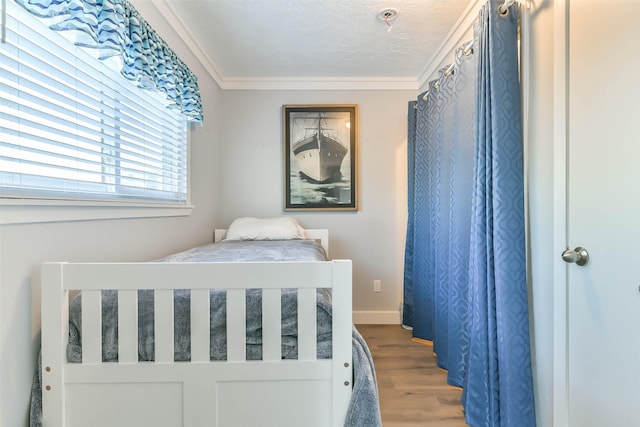 bedroom with wood finished floors, baseboards, and ornamental molding
