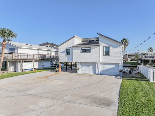 back of house featuring a lawn, a garage, fence, concrete driveway, and a residential view