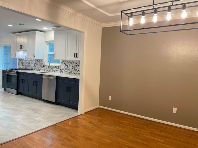 kitchen with stainless steel appliances, backsplash, light countertops, a sink, and light wood-type flooring