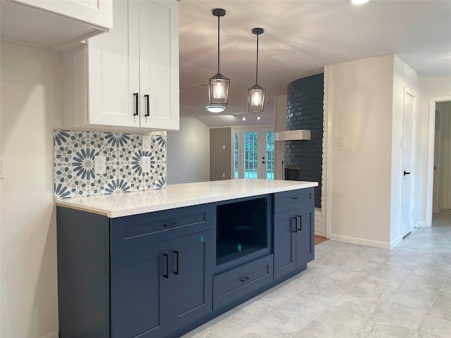 kitchen featuring white cabinets, baseboards, decorative backsplash, light countertops, and hanging light fixtures