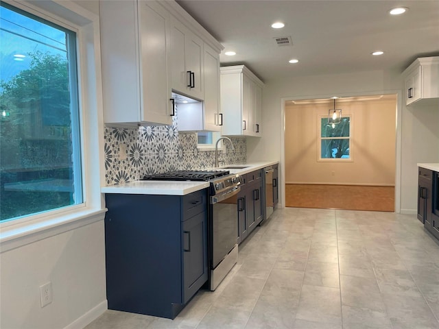 kitchen with visible vents, decorative backsplash, light countertops, and gas stove