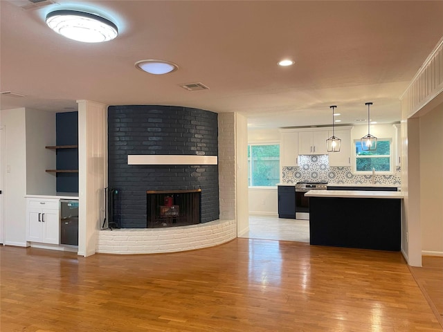 living room with recessed lighting, visible vents, light wood-type flooring, baseboards, and a brick fireplace