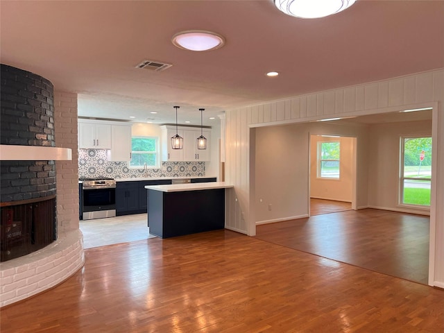 kitchen featuring light countertops, electric stove, visible vents, a sink, and open floor plan