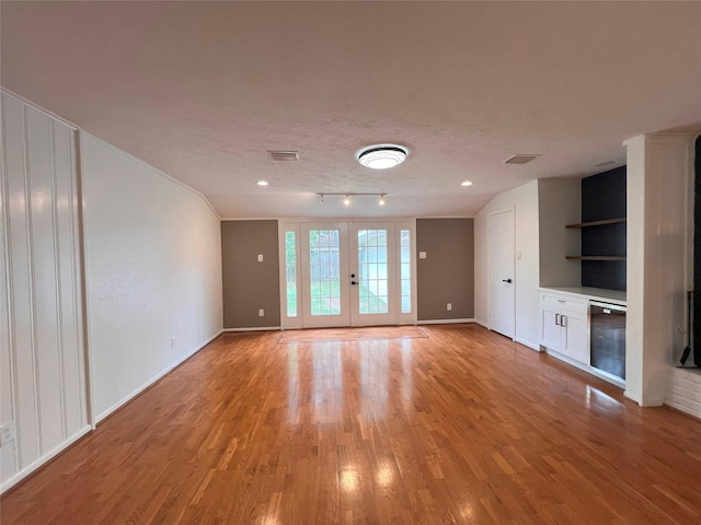 unfurnished living room featuring baseboards, visible vents, and light wood-style flooring
