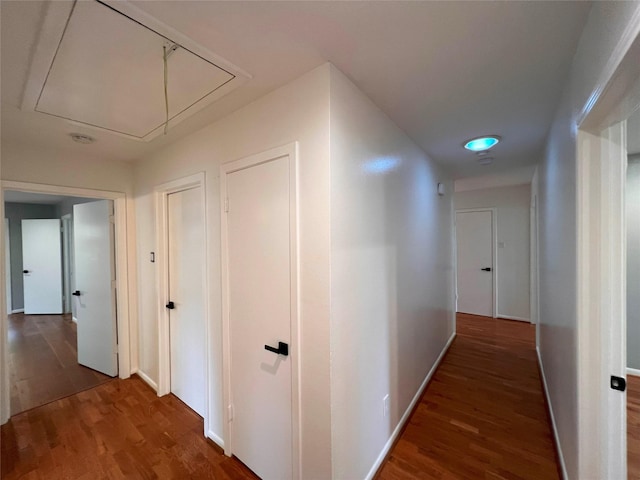 hall with attic access, baseboards, and wood finished floors