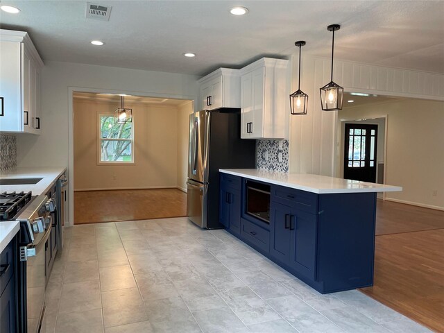 5475 Jackwood St, Houston, TX 77096 - kitchen featuring appliances with stainless steel finishes, blue cabinets, light countertops, white cabinetry, and a peninsula