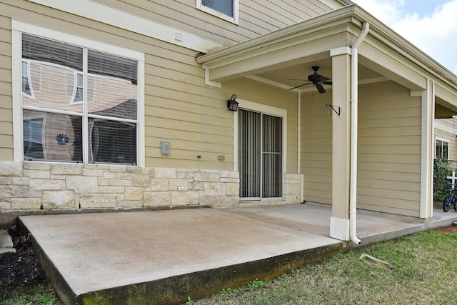 back of house featuring a patio, stone siding, and a ceiling fan