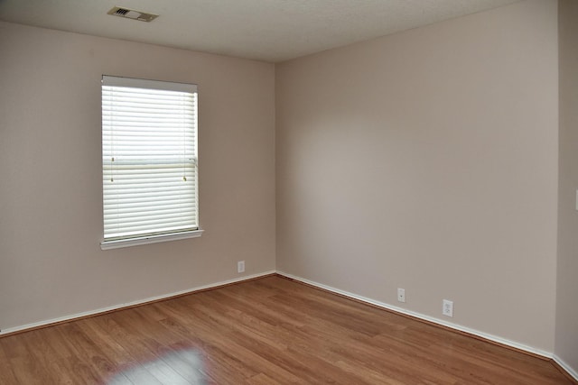 unfurnished room featuring visible vents, baseboards, and wood finished floors