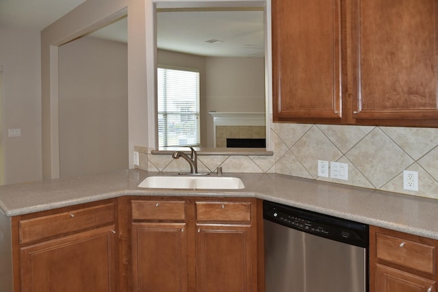 kitchen with dishwasher, a sink, light countertops, brown cabinetry, and backsplash