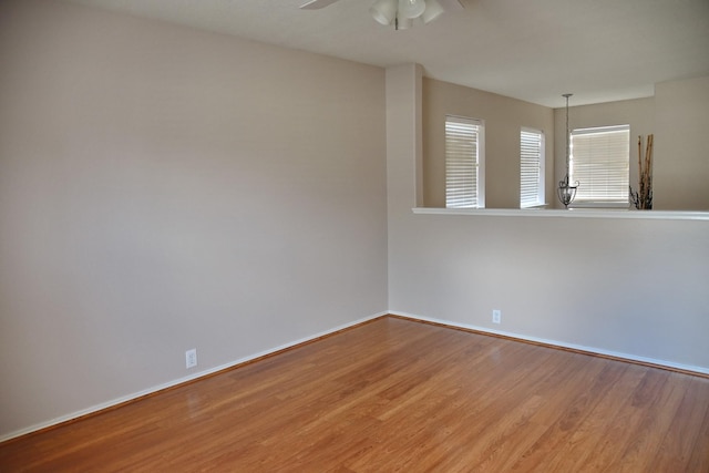 empty room with baseboards, a ceiling fan, and wood finished floors