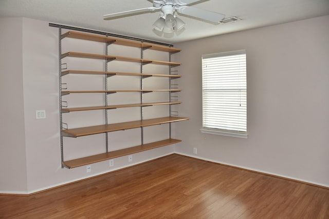 empty room with visible vents, baseboards, a ceiling fan, and wood finished floors
