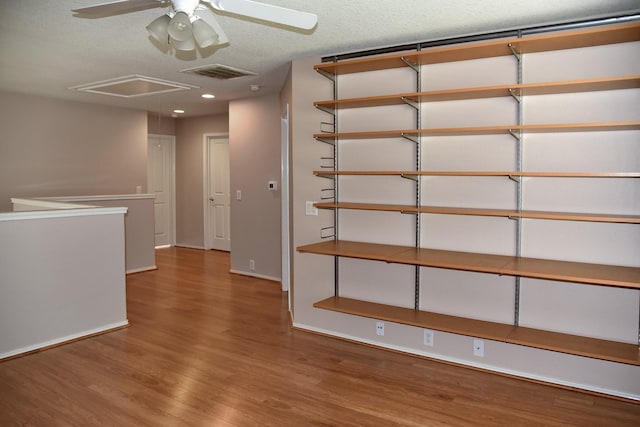 interior space featuring visible vents, baseboards, a ceiling fan, attic access, and wood finished floors