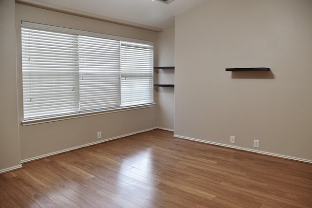 unfurnished room featuring baseboards and wood finished floors