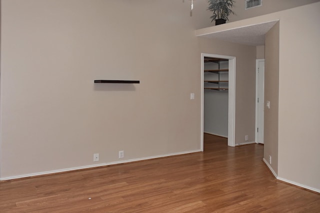 unfurnished room featuring visible vents, baseboards, and wood finished floors