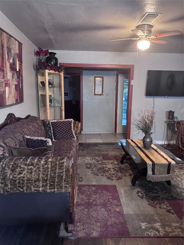 living area with a textured ceiling, visible vents, and ceiling fan