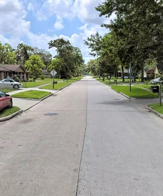 view of road with curbs, traffic signs, and a residential view