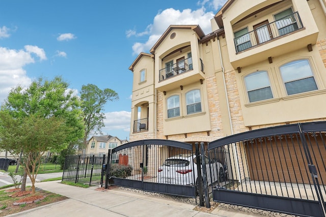 multi unit property with stucco siding, stone siding, and a fenced front yard