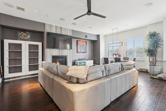 living room with ceiling fan, a fireplace, dark wood finished floors, and visible vents
