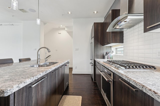 kitchen with a sink, wall chimney range hood, dark brown cabinets, and stainless steel appliances