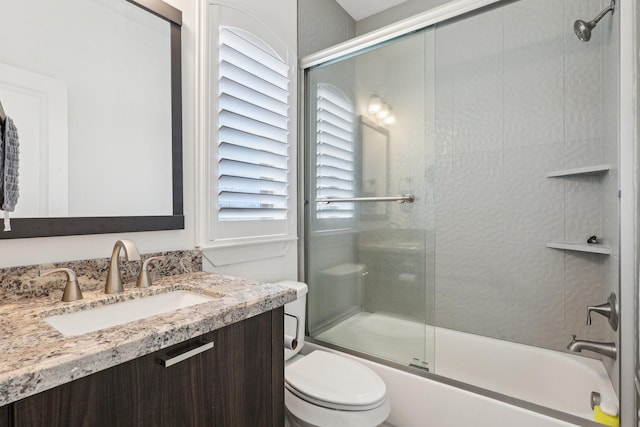 full bathroom with bath / shower combo with glass door, vanity, and toilet