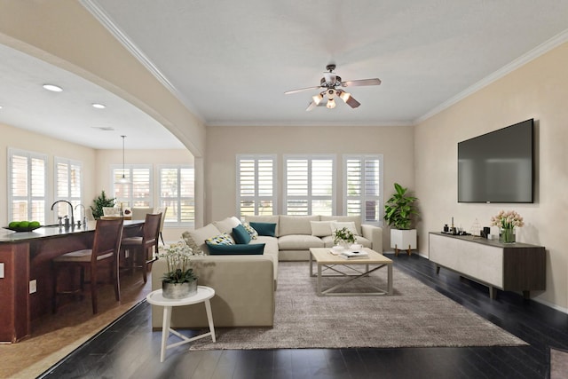 living room with dark wood-type flooring, a ceiling fan, arched walkways, and a healthy amount of sunlight