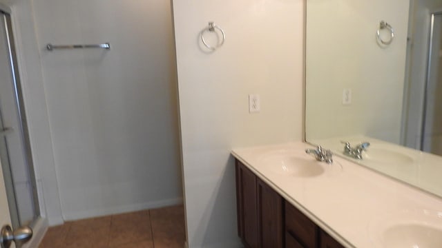 bathroom featuring a sink, tile patterned floors, double vanity, and baseboards