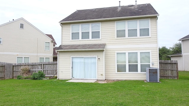 back of property with roof with shingles, a lawn, fence, and central AC