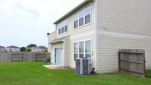 back of property with a yard, fence, and central AC unit