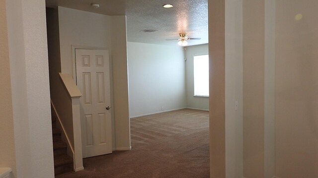 corridor with visible vents, baseboards, carpet flooring, and a textured ceiling