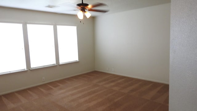 carpeted empty room featuring a healthy amount of sunlight, baseboards, and a ceiling fan