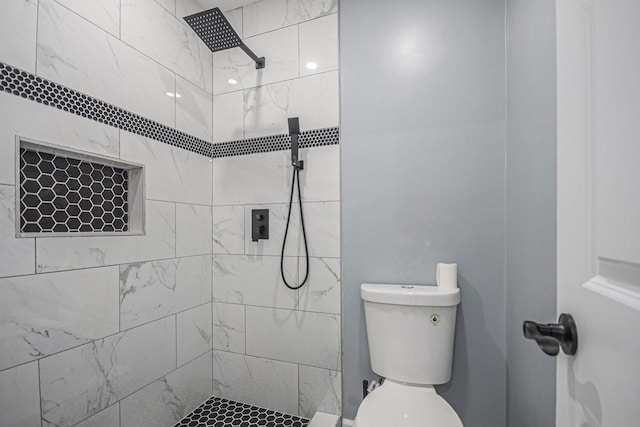 bathroom featuring a tile shower and toilet