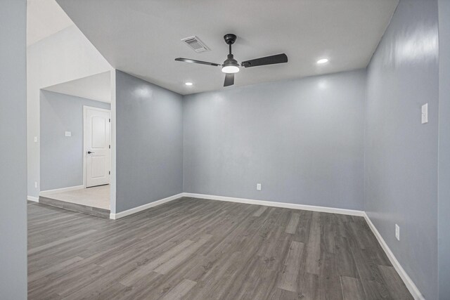 empty room with baseboards, visible vents, wood finished floors, and a ceiling fan