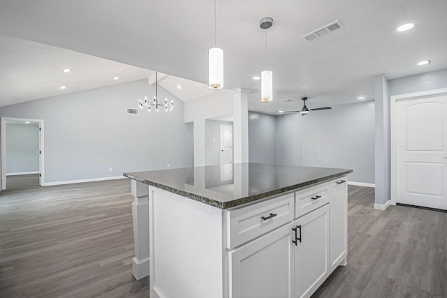 kitchen featuring wood finished floors, vaulted ceiling, baseboards, visible vents, and open floor plan