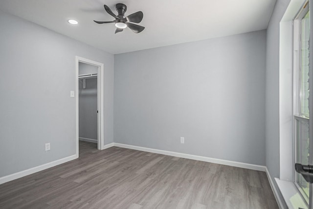 unfurnished bedroom featuring recessed lighting, wood finished floors, ceiling fan, a walk in closet, and baseboards
