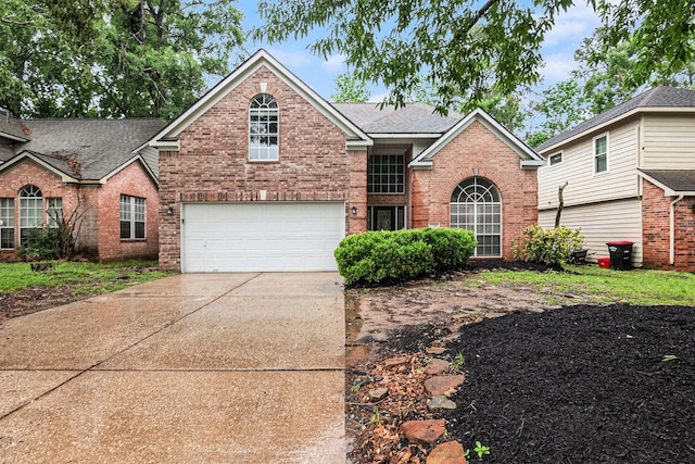 traditional-style house with concrete driveway, brick siding, roof with shingles, and a garage
