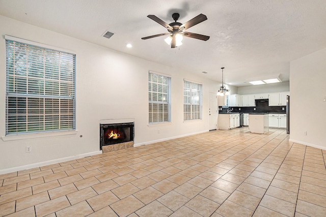 unfurnished living room featuring a tiled fireplace, visible vents, baseboards, recessed lighting, and ceiling fan