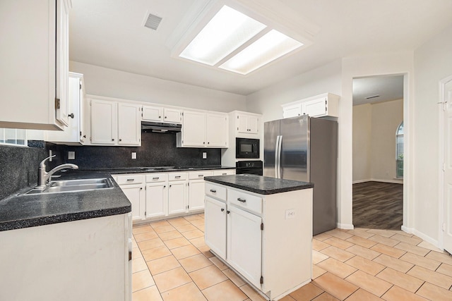 kitchen with a sink, white cabinets, black appliances, backsplash, and visible vents