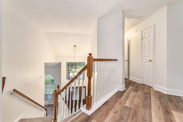 hallway with baseboards, wood finished floors, and an upstairs landing