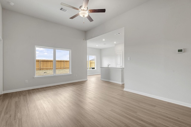 unfurnished living room with visible vents, baseboards, a ceiling fan, and light wood-style flooring