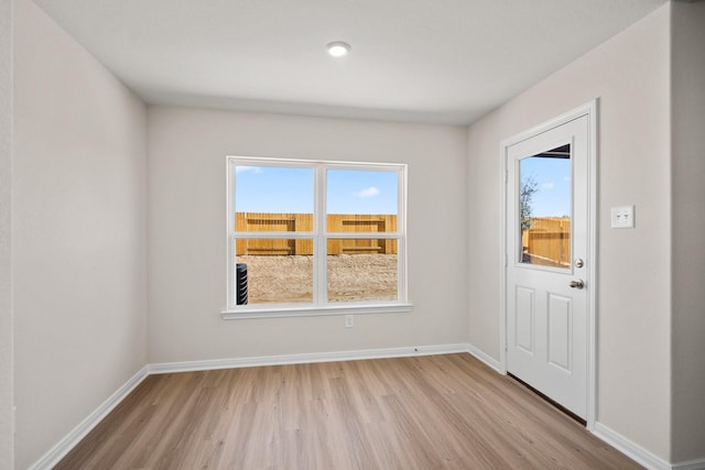 doorway featuring a wealth of natural light, light wood-type flooring, and baseboards