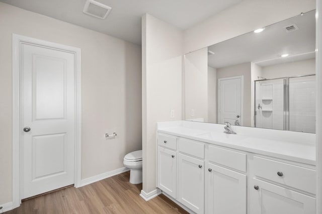 full bathroom with vanity, toilet, a shower stall, visible vents, and wood finished floors