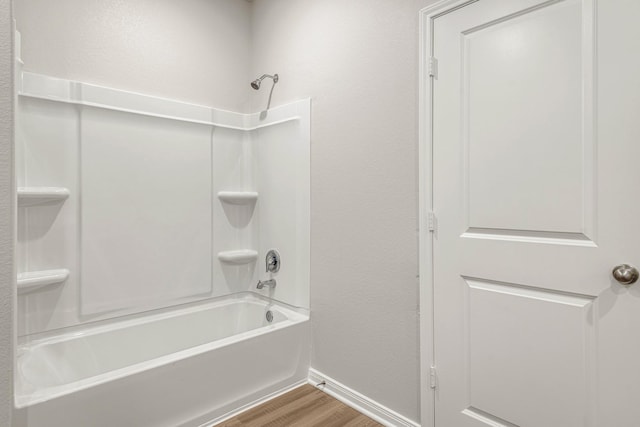 full bath with a textured wall, baseboards, wood finished floors, and  shower combination