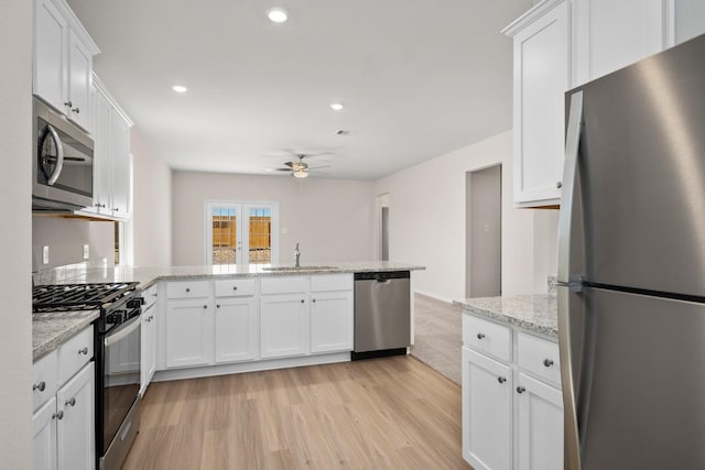 kitchen featuring ceiling fan, a peninsula, white cabinets, a sink, and stainless steel appliances