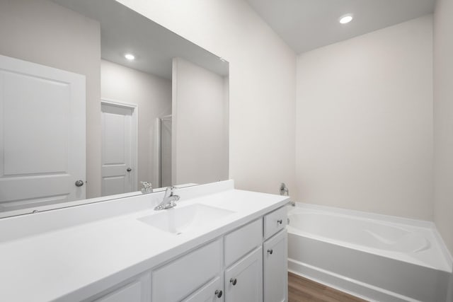 bathroom with vanity, a stall shower, recessed lighting, a garden tub, and wood finished floors