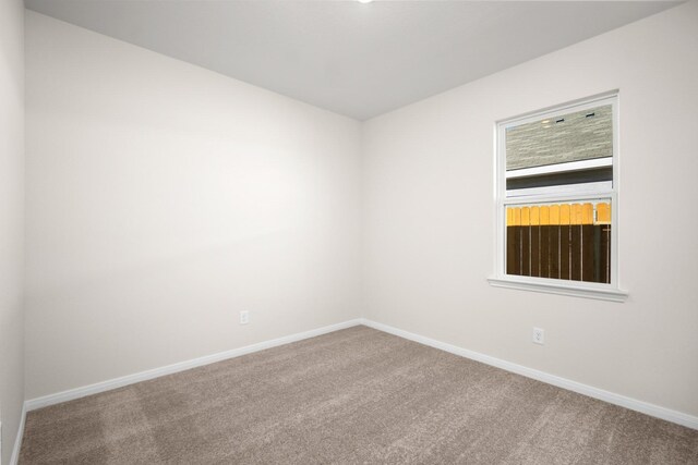 carpeted empty room featuring baseboards