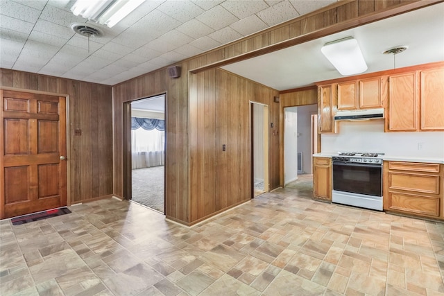 1220 San Felipe St, Angleton, TX 77515 - kitchen featuring visible vents, under cabinet range hood, wood walls, light countertops, and gas range oven