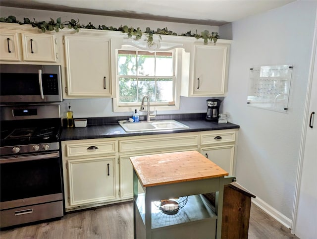 200 Commanche Rd, Conroe, TX 77316 - kitchen featuring dark countertops, light wood finished floors, a sink, and appliances with stainless steel finishes