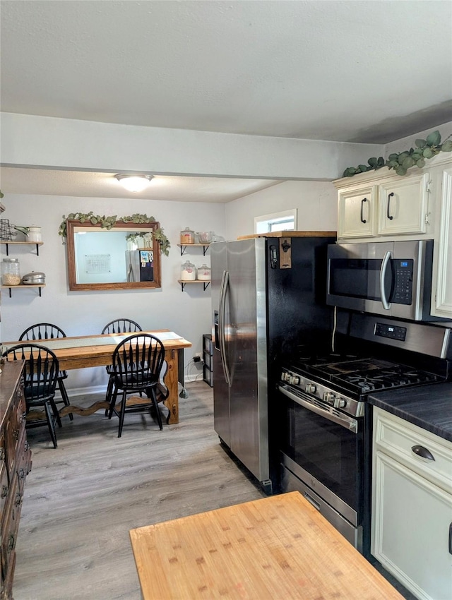 200 Commanche Rd, Conroe, TX 77316 - kitchen with dark countertops, light wood-style floors, baseboards, and appliances with stainless steel finishes