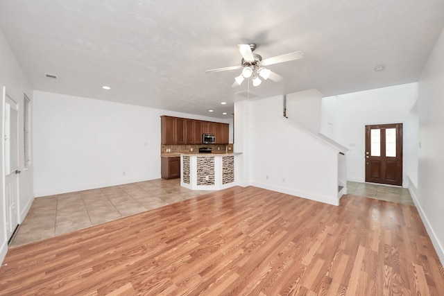 6 Whitekirk Pl, Magnolia, TX 77354 - unfurnished living room featuring ceiling fan, stairway, light wood-style floors, and baseboards